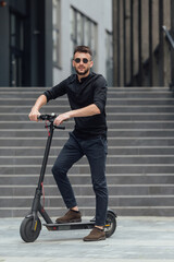 Young man riding electric scooter in urban background