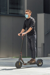 Young man riding electric scooter in medical mask in face