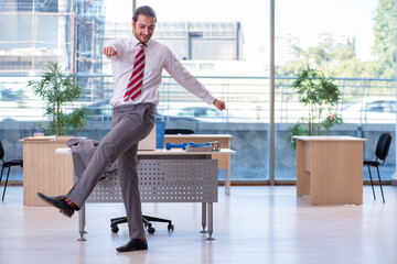 Young male employee doing sport exercises in the office