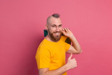 Happy bearded positive man casual look with colorful shopping bags studio pink background