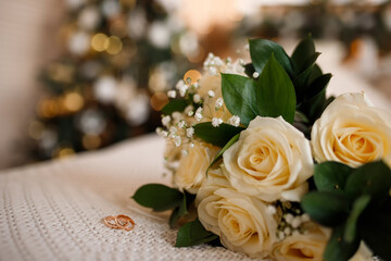 Wedding rings near a wedding bouquet of red and white roses.