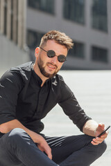 Young man sitting on  electric scooter with phone in urban background