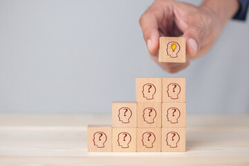 Hand business picked wooden cube block with head human symbol and light bulb icon  creative idea concept.