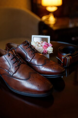 The groom is gathering in the morning. Men's classic patent leather shoes black belt and boutonniere Wedding details.