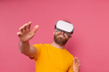Handsome positive bearded man touching air in vr glasses studio background
