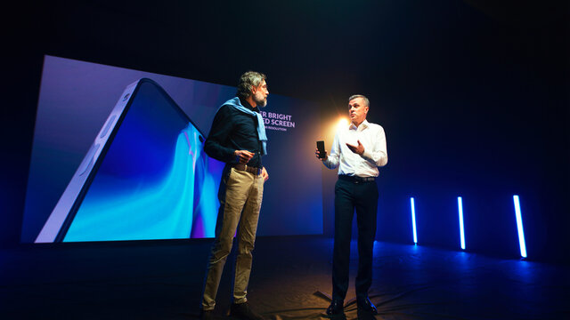 Male speakers discussing new smartphone on stage