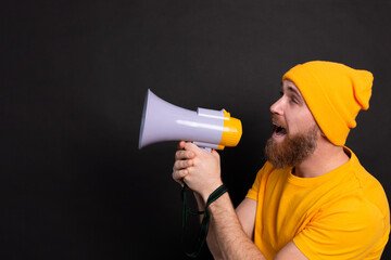 Attention! European man shouting in megaphone on black background