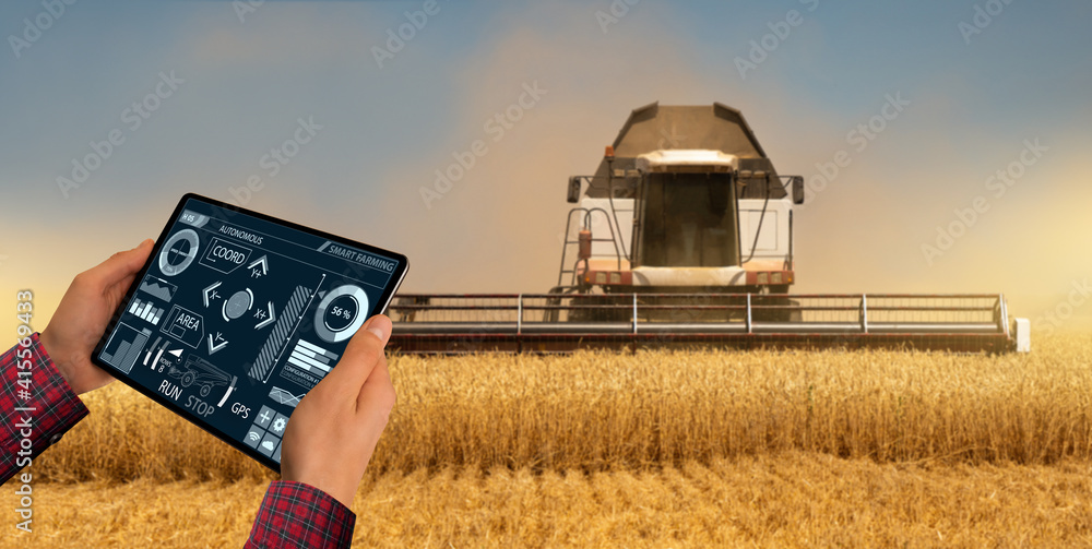 Poster Remote control of an autonomous combine in the field.  Farmer  with a digital tablet in the agricultural field.