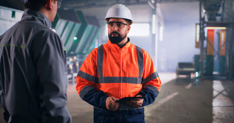 Male inspector speaking with worker on factory