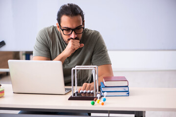 Young male student physicist preparing for exams in the classroo