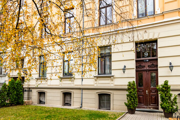 Entrance into yellow and cream colour art nouveau home at Riga centre during autumn day when birch leaves are yellow and framing entrance