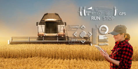 Remote control of an autonomous combine in the field.  Farmer  with a digital tablet in the...