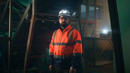 Male engineer looking at camera near machinery