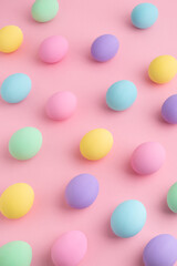 Pastel colored Easter eggs scattered on pink background. Easter Day colorful pattern, abstract flat lay.