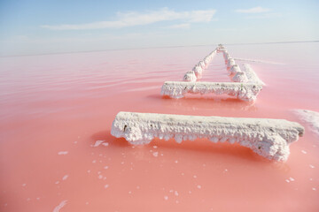 Wooden pillars of the destroyed bridge stick out of the natural red water in the place of salt...