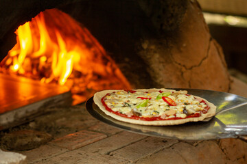 Italian pizza cooking in a traditional brick wood oven