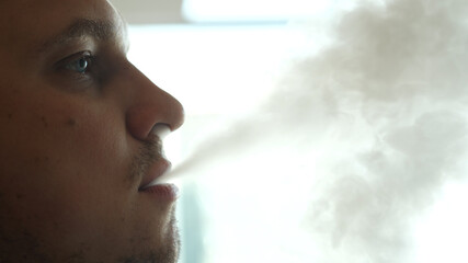 Close-up of man inhaling an e-cigarette vaping device. slow motion