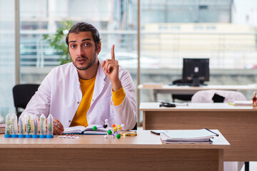 Young male chemist in drug synthesis concept