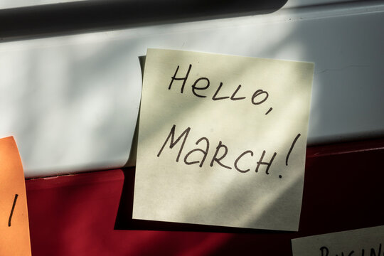 Hello March. The Greeting Message Is Written With A Marker On A Red Adhesive Paper Sticker. The Arrival Of Spring, The Imminent Flowering