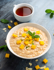 Rice pudding with cinnamon and mango in white bowl