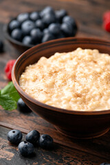 Rice pudding with cinnamon and blueberry, raspberry in rustic bowl