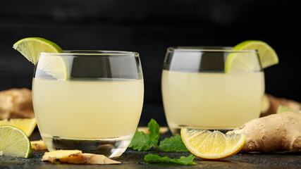 Ginger and lemon beer sparkling fizzy drink in glasses with lime wedges on the side