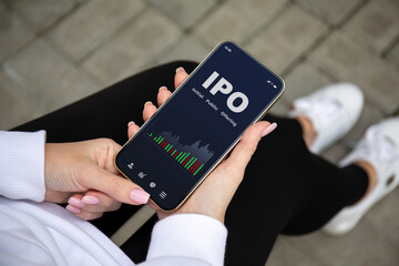 female hands holding the phone with IPO stocks purchase app