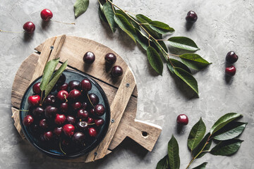 top view of red cherries on a bowl with slices of peaches on a wooden kitchen board with knife on a...