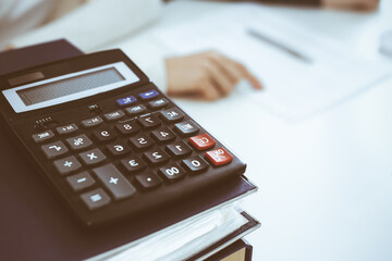 Calculator and binders with papers are waiting to be processed by business woman or bookkeeper...