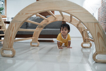 baby crawling past under the pikler climbing toys in the house
