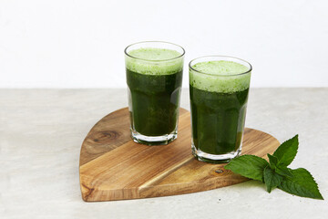 Green smoothies with chlorella, cucumber, green apple and spinach on a wooden board.