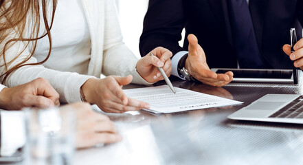 Business people discussing contract working together at meeting in modern office. Unknown businessman and woman with colleagues or lawyers at negotiation