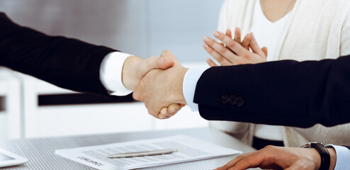 Business people shaking hands after contract signing in modern office. Teamwork and handshake concept