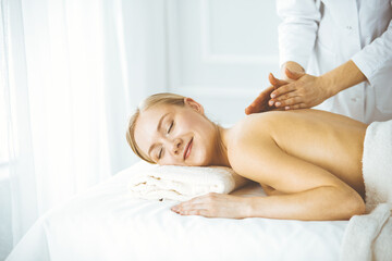 Fototapeta na wymiar Beautiful happy woman enjoying back massage with closed eyes. Beauty and Spa salon concept