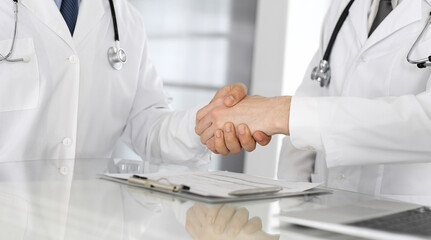 Two doctors are shaking hands as agreement about patient's treatment, close-up. Medical help, medicine concept