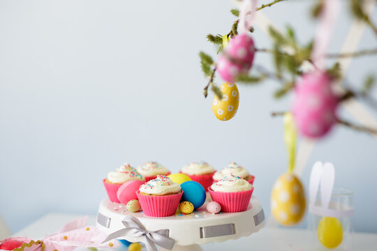 Easter sweets and decorations - cupcakes, colorful painted eggs and copy space over blue background