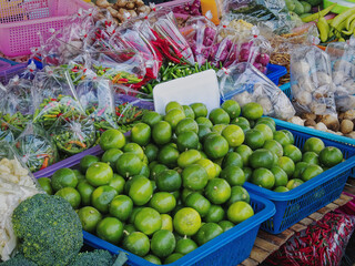 Close-up Pile of Fresh Green Limes and Various Kinds of Vegetables for Sale at Market Stall