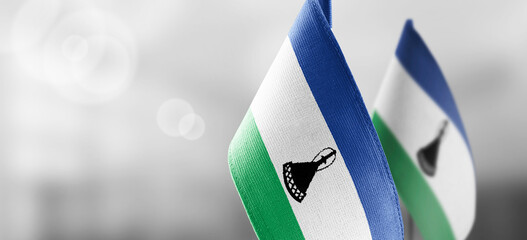 Small national flags of the Lesotho on a light blurry background - obrazy, fototapety, plakaty