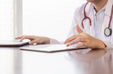 Healthcare and medical concepts. Doctor working with tablet smartphone and stethoscope in modern office, writing prescription clipboard with record information on desk