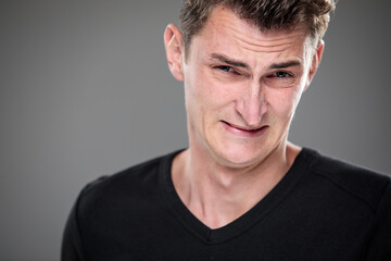 Obraz premium Fear/anxiety/regret/uncertainty in a young man - effects of a difficult life situation - vivid emotions concept