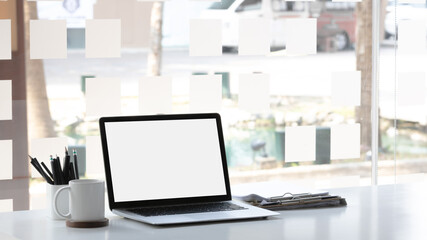 Laptop computer with mockup or blank screen on white desk in workspace and copy space concept