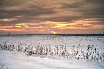 Naklejka premium a field covered with snow at sunset