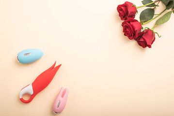 Flat lay from female masturbation accessories. Vibrators and roses on a peach background. Copy space