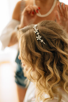 Stylist puts on a hairpin in the bride's hairstyle during wedding preparations 