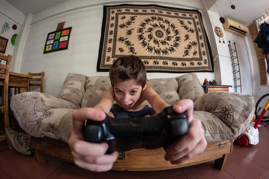 Ni&ntilde;o juega con joystick mira a c&aacute;mara jugando serio 
