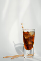 Glass of cola with ice and straw on a white background