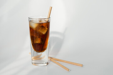 Glass of cola with ice and straw on a white background