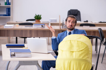 Young male employee looking after new born at workplace