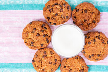 Delicious homemade cookies with chocolate and a glass cup of milk on a wooden table. Beautiful still life