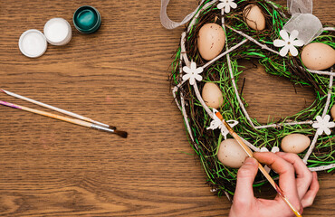 Young man decorating Easter wreath on a table. Flat lay, top view